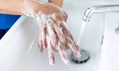 Adam ellerini lavaboda yıkıyor. Temizlik için colona virüsünü temizliyor ve COVID-19 'un tüm dünyaya yayılmasını engelliyor..