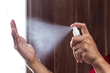 Adam bakteri ve virüslerden kurtulmak için alkol spreyi kullanıyor, Covid-19 virüs enfeksiyonunu önlemek için yüzde 70 alkol kullanıyor, virüs konseptini koruyor..