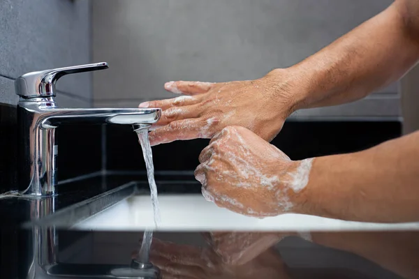 Man is washing his hands in a sink sanitizing the colona virus for sanitation and reducing the spread of COVID-19 spreading throughout the world, Hygiene ,Sanitation concept.