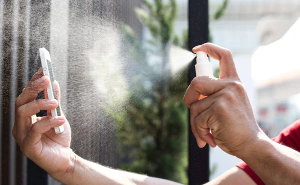 Erkekler cep telefonlarındaki bakteri ve virüslerden kurtulmak için alkol spreyi kullanıyor, yüzde 70 alkol kullanarak, virüs konseptini korumak için Covid-19 virüs enfeksiyonunu engelliyor ve engelliyor.