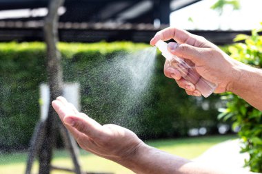 Adam bakteri ve virüslerden kurtulmak için alkol spreyi kullanıyor, Covid-19 virüs enfeksiyonunu önlemek için yüzde 70 alkol kullanıyor, virüs konseptini koruyor..