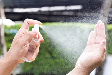 Adam bakteri ve virüslerden kurtulmak için alkol spreyi kullanıyor, Covid-19 virüs enfeksiyonunu önlemek için yüzde 70 alkol kullanıyor, virüs konseptini koruyor..