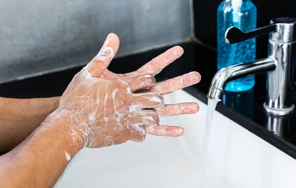 Man is washing his hands in a sink sanitizing the colona virus for sanitation and reducing the spread of COVID-19 spreading throughout the world, Hygiene ,Sanitation concept.