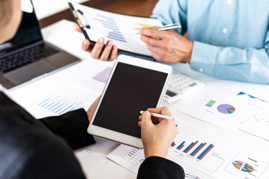Şirketin gelir grafiğiyle ilgili iş adamları, yöneticiler ve muhasebecilerden oluşan bir ekiple ofiste dizüstü bilgisayarlar, hesap makineleri ve finans konseptiyle bir araya gelmek.