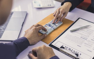 İşadamları, yasadışı arazi ve gayrimenkul, iş dolandırıcılığı ve sosyal adaletsizlik, yolsuzluk ve rüşvet kavramını satın almak için sözleşmeler imzalayan çalışanlara dolar dağıtıyor.