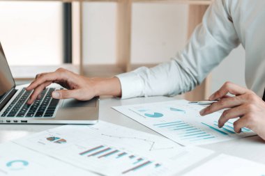 Finans işadamları, müşterileri, Muhasebe ve Vergi kavramlarının şirket vergilerini azaltmak için pazarlama stratejilerini ve emlak verilerini analiz etmek için dizüstü bilgisayar kullanıyorlar..