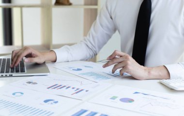 Finans işadamları, müşterileri, Muhasebe ve Vergi kavramlarının şirket vergilerini azaltmak için pazarlama stratejilerini ve emlak verilerini analiz etmek için dizüstü bilgisayar kullanıyorlar..