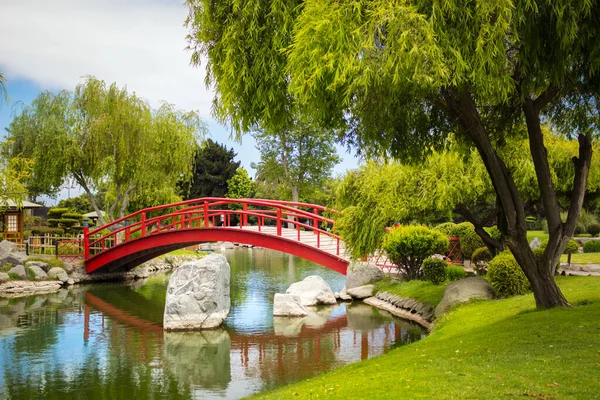 セレナの日本庭園の池の下の美しい赤い橋 ストック画像