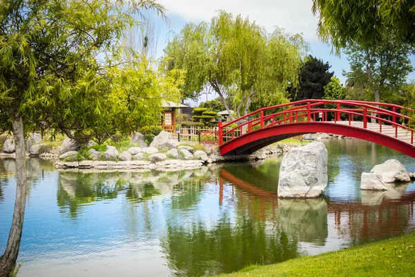セレナの日本庭園の池の下の美しい赤い橋 ストックフォト