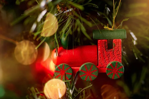 Ağaçta asılı Noel oyuncağı kırmızı tren yeşil iğneler ve renkli bokeh