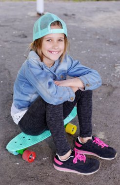Küçük kız onun mavi paten kurulu açık tutarak. Kaykay kız stil