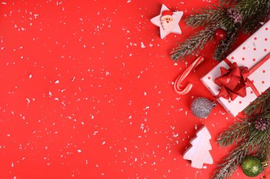 Kırmızı arka planda Noel kompozisyonu. Düz oturma odası, üst görünüm, metin için kopyalama alanı. Noel süsleri hediyeler, ladin, oyuncaklar, şekerler, yıldızlar, karlı kırmızı bir zemin üzerinde.