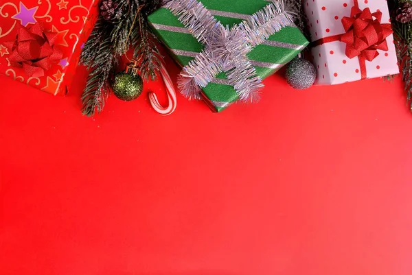 Kırmızı arka planda Noel kompozisyonu. Düz oturma odası, üst görünüm, metin için kopyalama alanı. Noel süsleri hediyeler, ladin, oyuncaklar, şekerler, yıldızlar, karlı kırmızı bir zemin üzerinde.