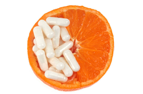 Capsules of food supplements in half an orange close-up on a white background 