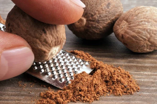 Grating fresh nutmeg close up wiith kitchen utensil