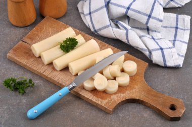 Avuç içi kalpler kesme tahtasının üzerinde. Gri arka planda maydanoz filizi var.