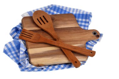 Cutting board and wooden cutlery on a tea towel close-up on a white background