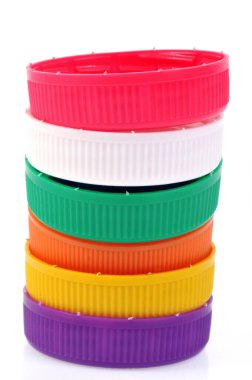 Plastic cap of different colors stacked close-up on white background