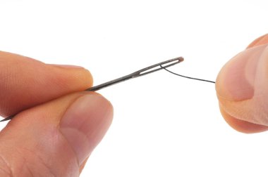 Pass the thread in the case of a sewing needle close-up on a white background 