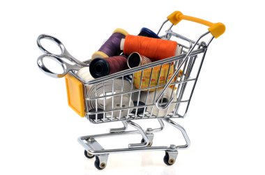 Supermarket cart with sewing equipment close-up on white background