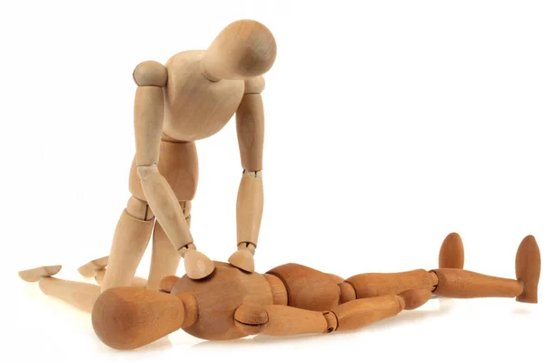 Wooden mannequin doing a heart massage on another mannequin on a white background