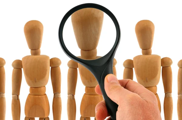 Examination of wooden mannequins with a magnifying glass
