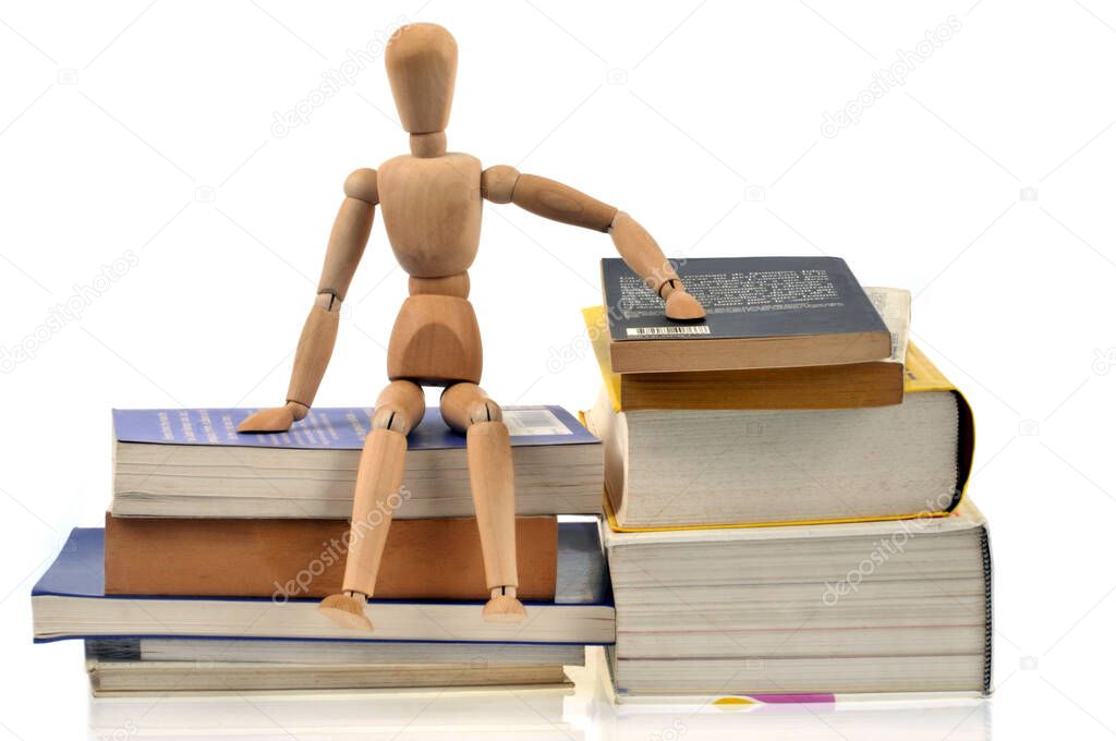 Wooden mannequin sitting on books on white background