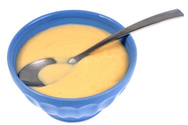 Beyaz arka planda kaşıkla kaplanmış bir kase muhallebi.