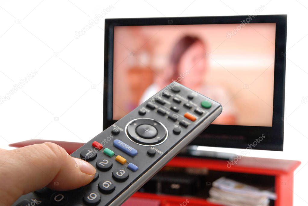 Remote control by hand in front of a TV 