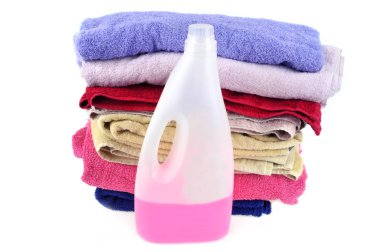 Sıvı deterjan kutusu ve banyo havlusu yığını beyaz arka planda.