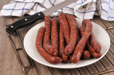 Bıçağın yanındaki tabakta çiğ merguez tabağı.