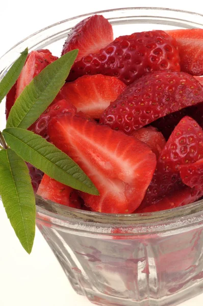 Ramekin of strawberries with lemon verbena leaves close-up on white background