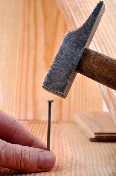 Hammering a flat head nail with a hammer close up