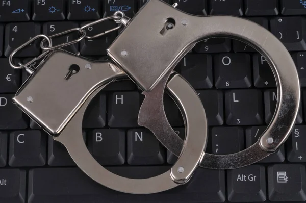 Hacker concept with handcuffs on a computer keyboard close up