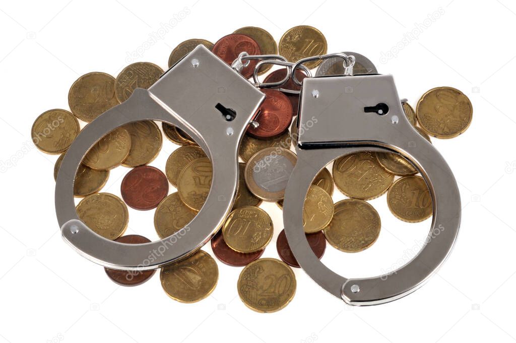 Tax fraud concept with handcuffs on coins close up on white background