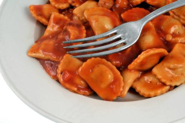 Beyaz arka planda çatallı ravioli tabağı.