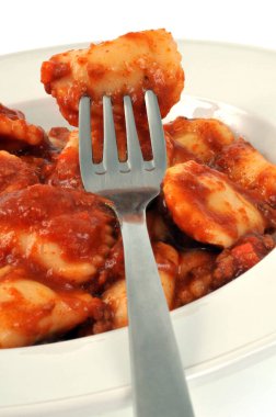 Beyaz arka planda çatallı ravioli tabağı.