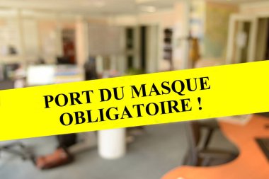 Sarı bir pankarta zorunlu maske takmış.