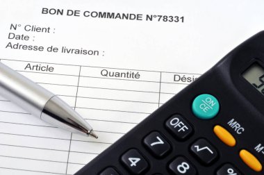 Bir sipariş formuna yerleştirilmiş hesap makinesi ve kalem