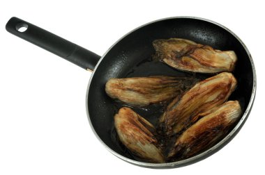 Beyaz bir arkaplanda bir tavada ağır ateşte pişirilmiş hindiba. 