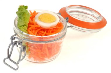 Kavanozda haşlanmış yumurta ve beyaz arka planda salata yaprağı ile rendelenmiş havuç.