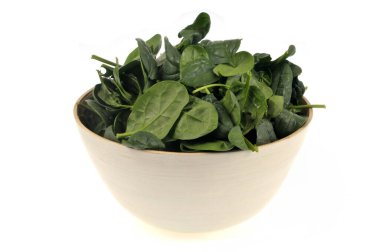 Beyaz arka planda bir kase ıspanak yaprağı.