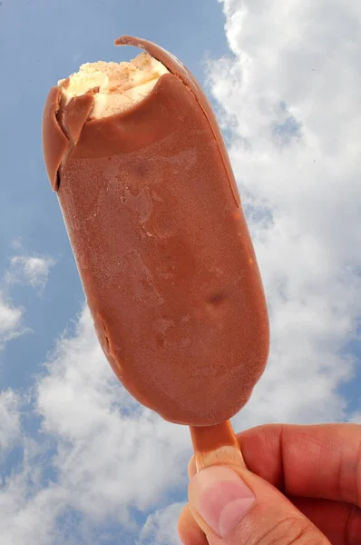 Bastoncino Cioccolato Alla Vaniglia Mano Con Cielo Nuvoloso Sullo Sfondo — Foto Stock