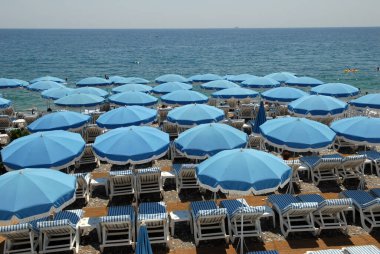 Şemsiyeler ve şezlonglar yazın Nice 'te Fransız Rivierası' nda sahilde.