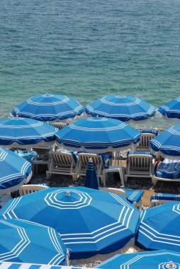 Şemsiyeler ve şezlonglar yazın Nice 'te Fransız Rivierası' nda sahilde.