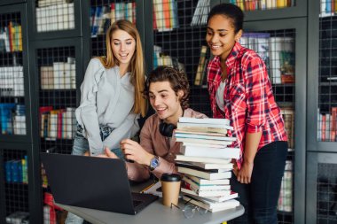 Kütüphanede öğrenen üç mutlu öğrenci, seçici odaklanma