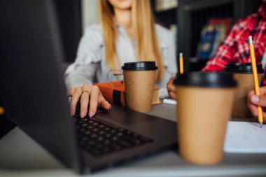 Kütüphanede okurken yakın çekim, masada kahve fincanları.