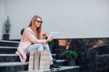 Alışveriş torbalarıyla güzel sarışın kadın, seçici bir odak noktası.