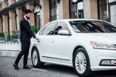Yeni beyaz arabanın yanındaki yakışıklı genç işadamı, seçici odaklı.
