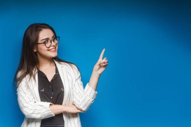 Genç ve güzel bir kadın mavi arka planda poz veriyor